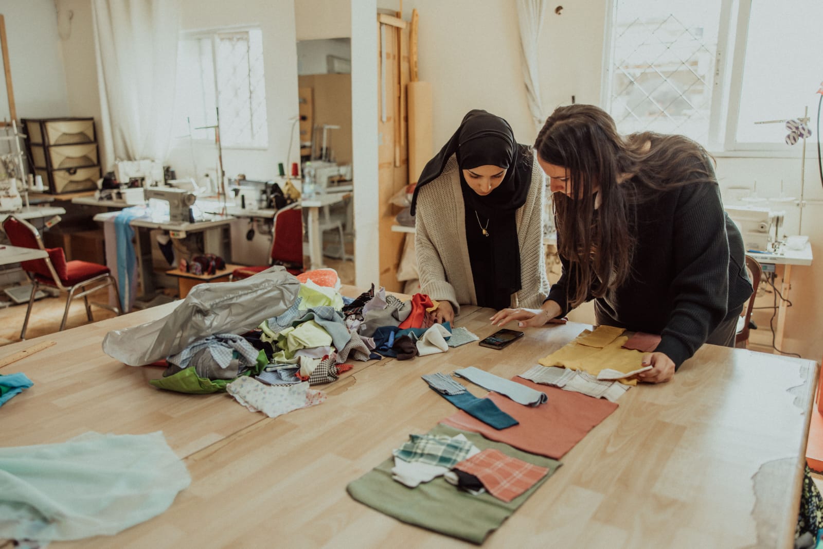Two Fabrica artisans sorting salvaged fabrics in the Amman studio