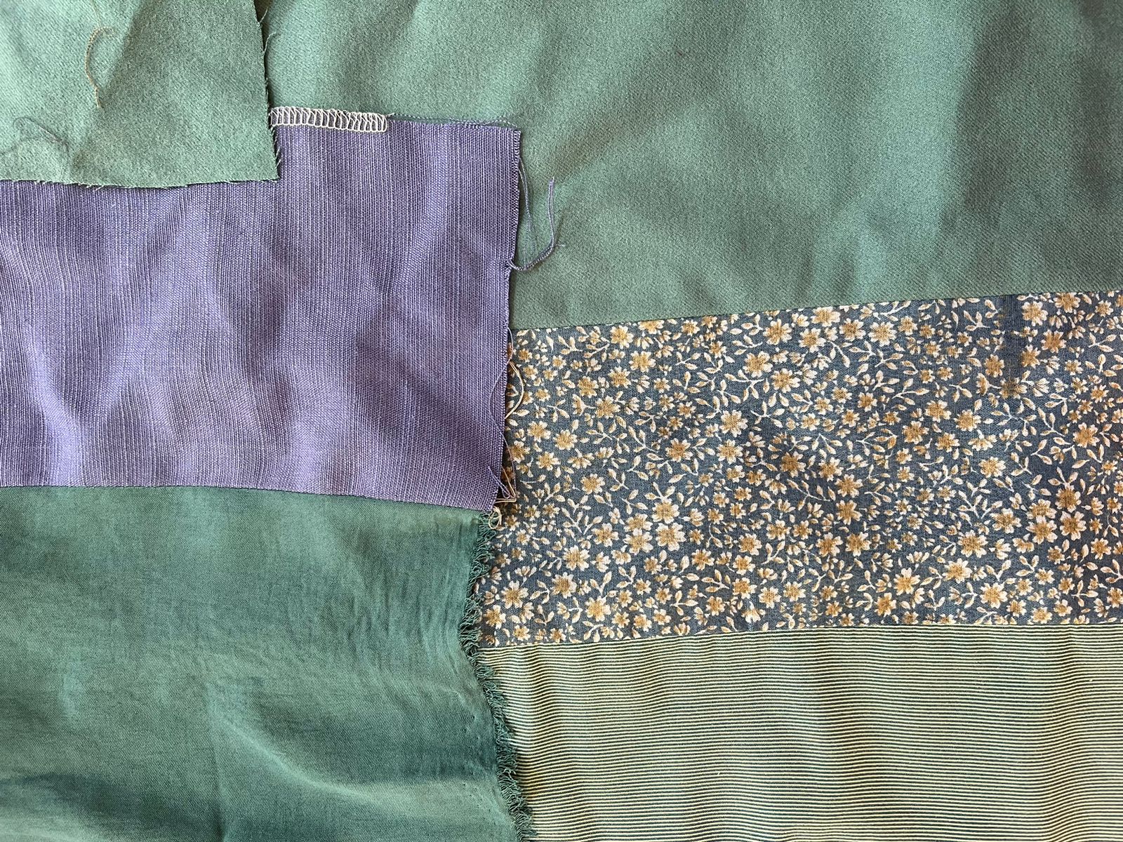 Close-up of a patchwork of rescued fabrics in sage green, lavender and floral prints